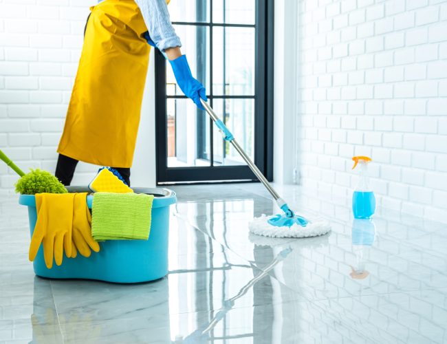 Wife housekeeping and cleaning concept, Happy young woman in blue rubber gloves wiping dust using mop while cleaning on floor at home.